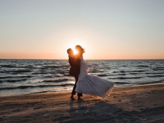 A Groom and Bride Dancing at Sunset Over A Beach Next To The Ocean