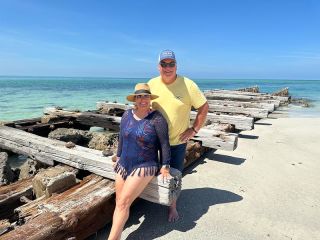 A Man And Woman Sitting On A Log On A Beach